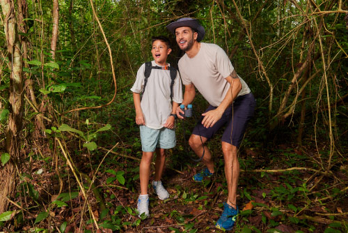 Un hombre y un niño, que usan ropa cómoda, están en medio de abundante vegetación disfrutando de la variedad de planes vacacionales en Lagosol