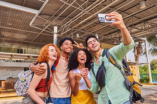 Dos mujeres y dos hombres jóvenes tomándose una fotografía en la recepción luego de acceder a la oferta en el hotel Lagosol 6 días. Alrededor se ve un gran techo de estructura metálica, tejas y naturaleza