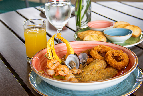Imagen del menú incluido en los planes en Lagomar, muestra un plato con camarones, aros de cebolla, pescado apanado, ostras y un vaso de jugo