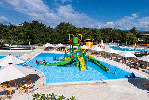 Fotografía del hotel y parque acuático Lagosol, que muestra la zona de piscina para niños con un rodadero y tobogán acuático de color verde con amarillo