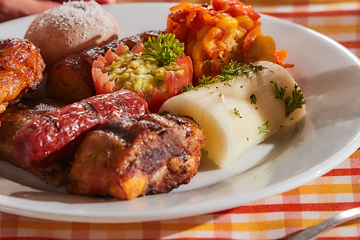 Imagen de la comida que se ofrece en los planes vacacionales en Lagosol, que muestra un plátano, una yuca, un chorizo, un tomate, una papa salada y una presa de pollo