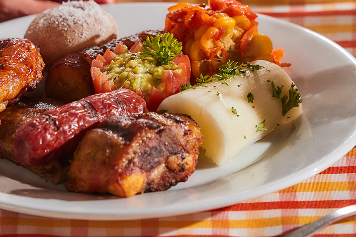 Imagen de la comida de los planes vacacionales en Lagosol, que muestra un plátano, una yuca, un chorizo, un tomate, una papa salada y una presa de pollo