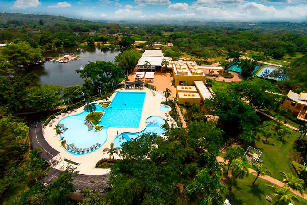 Vista panorámica del hotel y parque Lagosol, que muestra tres piscinas, zonas verdes, palmeras y un lago