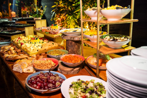 Mesa buffet con variedad de platos fríos, ensaladas, frutas y panes, organizada para la cena de Año Nuevo en Lagomar, con decoración festiva y ambiente nocturno