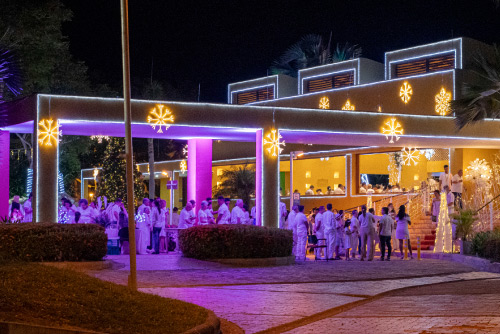Entrada principal adornada con figuras, luces y detalles navideños, donde un grupo de personas se reúne para celebrar la época decembrina en un ambiente cálido y festivo
