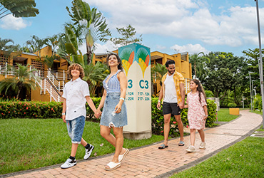 Familia de cuatro personas, dos adultos y dos niños, están caminando por los pasillos externos de las habitaciones en Lagosol