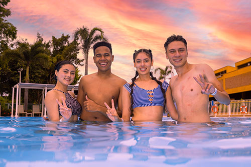 Cuatro jóvenes, dos hombres y dos mujeres, dentro de una piscina compartiendo un momento juntos y disfrutando de los planes de dos noches, tres días en Hotel Lagosol
