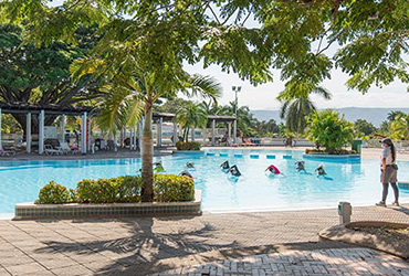 Piscina principal del hotel petfriendly Lagomar, en la que hay nueve personas haciendo aeróbicos y un instructor dirigiéndolos