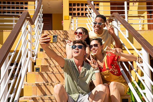 Dos hombres y dos mujeres, sonriendo, mientras se toman una foto sentados en las escaleras, alegres por sus planes en el Hotel Lagosol
