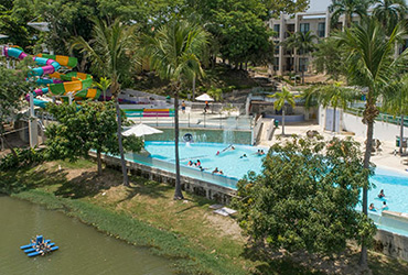 Plano contrapicado de las instalaciones de Lagomar hotel y centro de convenciones que muestra las palmeras, el lago, la piscina principal y dos toboganes