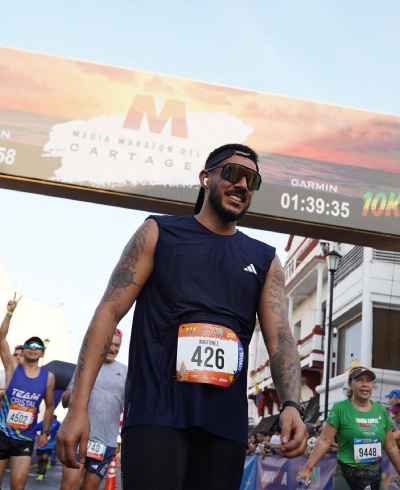 Corredor, con ropa deportiva de color azul, está cruzando la meta de una carrera que se lleva a cabo en las calles de Cartagena