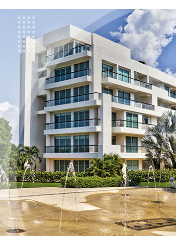 Edificio blanco de varios pisos rodeado de palmeras, jardines y fuentes de agua, en un lugar ideal para disfrutar una promoción de hoteles todo incluido en Cartagena.