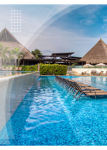 Piscina con sillas asoleadoras dentro del agua, rodeada de palmeras y construcciones con techo en palma, perfecta para quienes buscan reservas en el hotel Playa Manzanillo con descuento.
