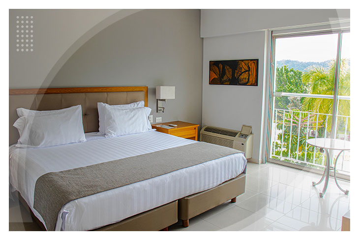 Espaciosa habitación con cama doble, mesa de noche, aire acondicionado, y un balcón que ofrece una vista al paisaje en el hotel Estelar Altamira