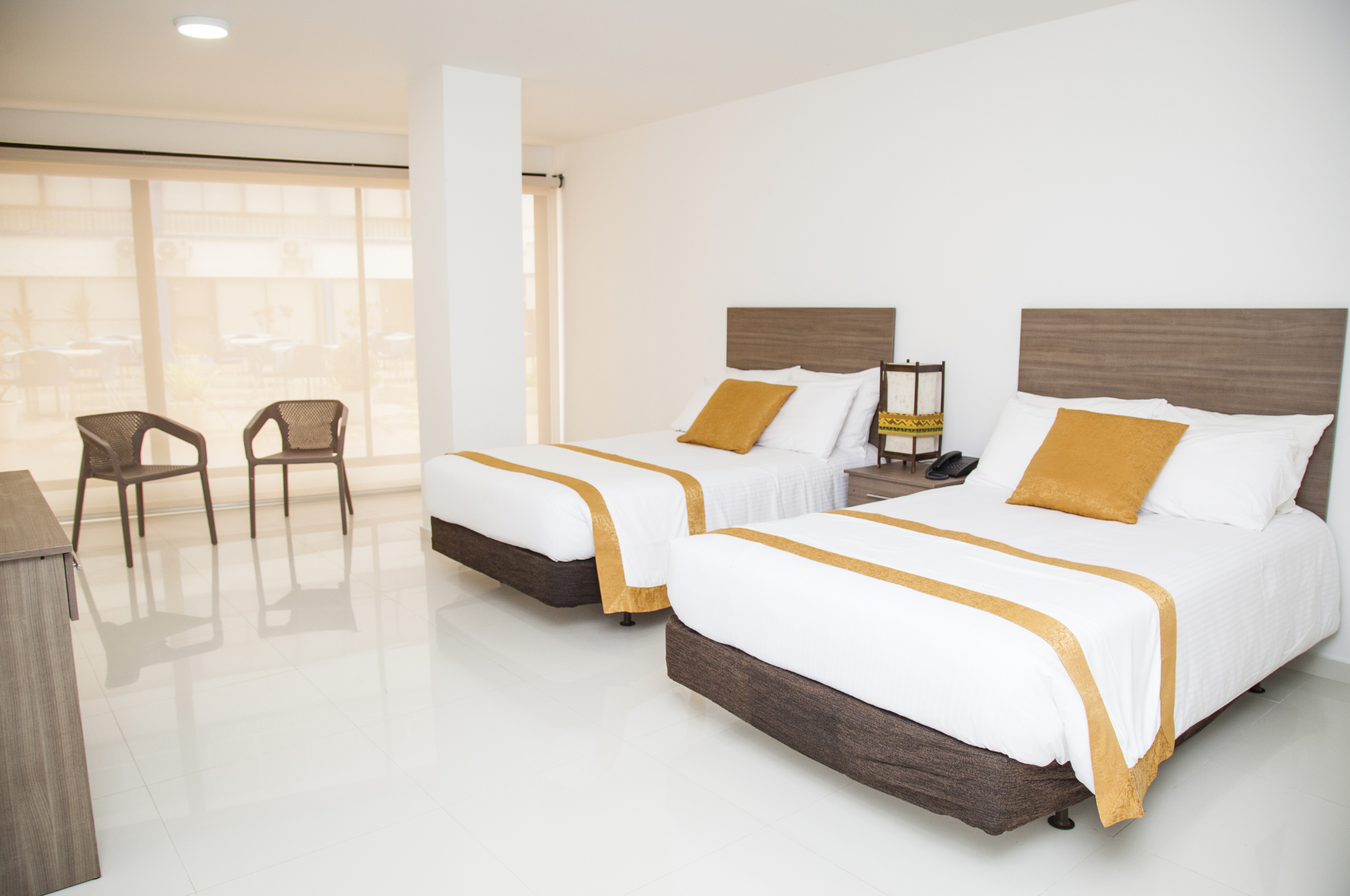 Habitación amplia con dos camas individuales, colchas blancas y detalles en tonos amarillos, diseñada para el descanso y disponible dentro de los paquetes hoteleros en San Andrés Compensar