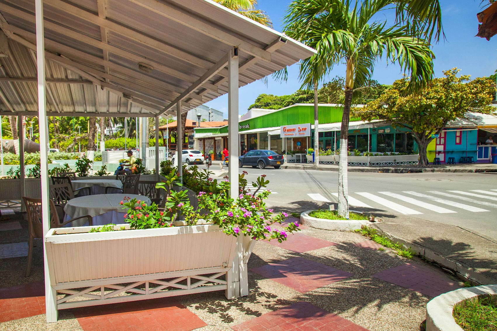 Área de restaurante al aire libre con mesas, vegetación tropical y vista a la calle, un espacio incluido dentro de los paquetes de hoteles Sol Caribe con descuentos disponibles en San Andrés