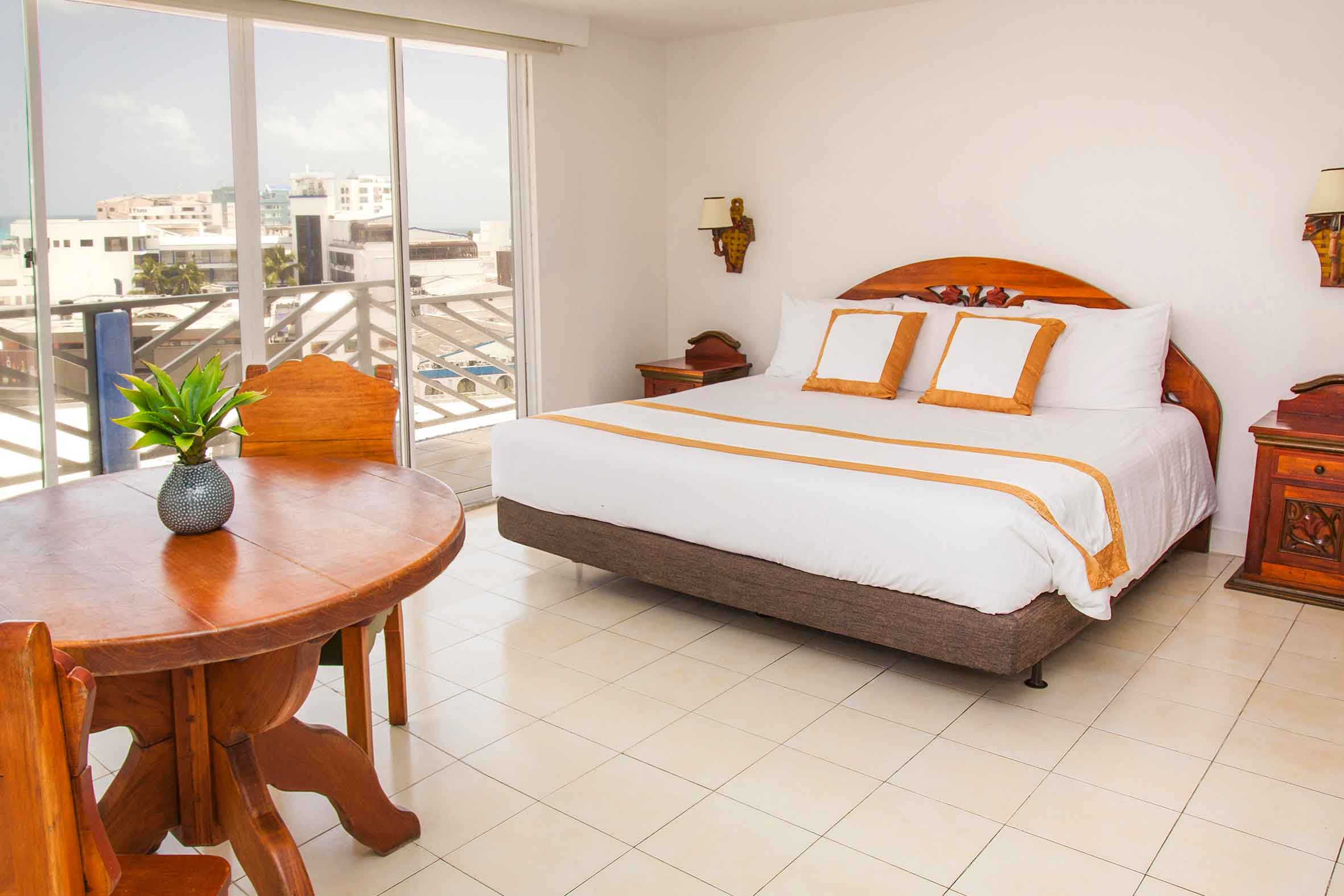 Habitación amplia y luminosa con cama doble, mobiliario en madera y balcón con vista urbana, pensada para quienes buscan una oferta de hoteles en San Andrés Compensar
