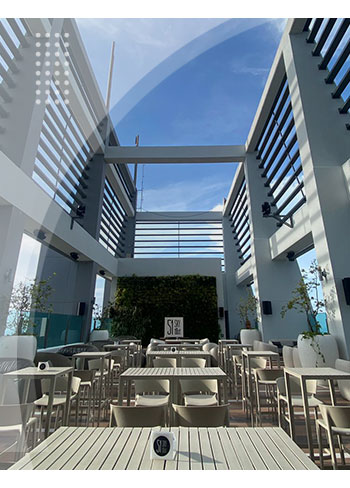 Terraza con mesas y sillas claras, cielo azul despejado, un ambiente fresco y elegante, hace parte de la experiencia que ofrecen los mejores hoteles en Cartagena.