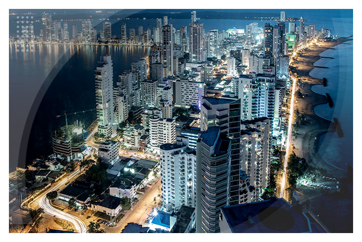 Vista de la ciudad de Cartagena al anochecer con edificios altos, calles iluminadas y el mar de fondo, ideal para quienes buscan habitaciones todo incluido en el Hotel Estelar y centro de convenciones.
