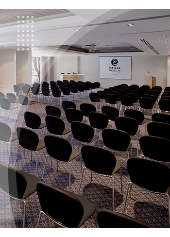 Auditorio amplio con sillas negras organizadas en filas, luz natural, pantalla de proyección, y espacios cómodos para reuniones, disponible como parte de la oferta del Hotel Estelar Parque de la 93.