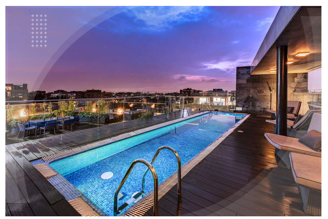 Piscina en la terraza con vista panorámica al atardecer, rodeada de sillas reclinables y un ambiente moderno y tranquilo, ubicada en uno de los hoteles de Bogotá cerca del Parque de la 93.