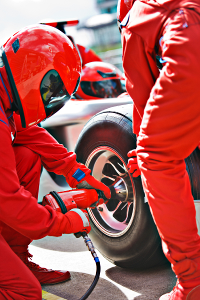 Equipo técnico con trajes y cascos rojos realizando un cambio de neumático a un monoplaza durante una parada en los pits, una escena que refleja la emoción que viven quienes adquieren el paquete de viaje Gran Premio de Brasil
