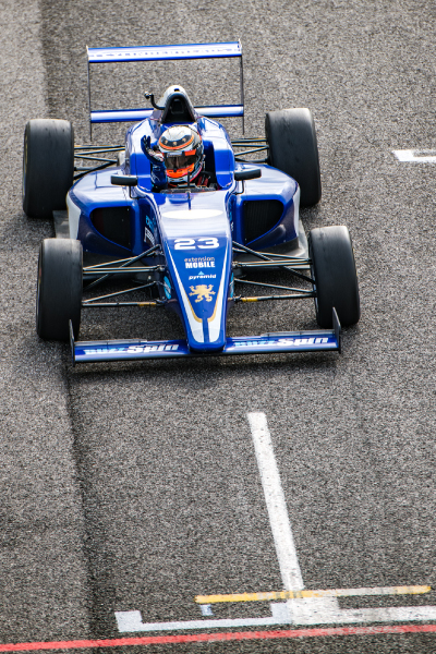 Monoplaza azul con el número 23 avanzando en un circuito profesional mientras el piloto alza su mano desde la cabina, imagen asociada a la entrada para el gran premio de São Paulo